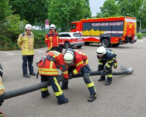 Das Foto zeigt mehrere Feuerwehrleute, die einen Wasserschlauch halten. Im Hintergrund sind Feuerwehrautos zu sehen. Foto: Heiko Schäfer / LRA