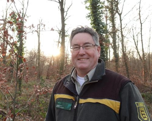 Das Foto zeigt den neuen Leiter des Forstreviers Bietigheim, Thomas Bauer. Er steht im Wald vor Bäumen.
