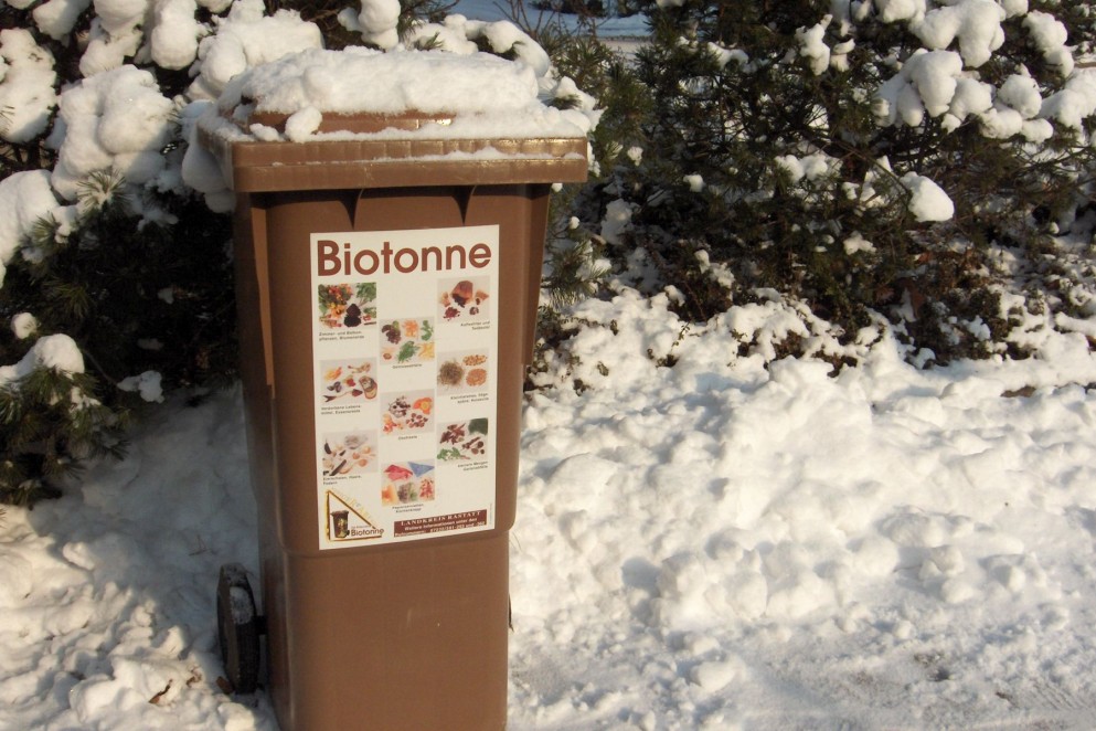 Das Foto zeigt eine braune Biotonne im Schnee.