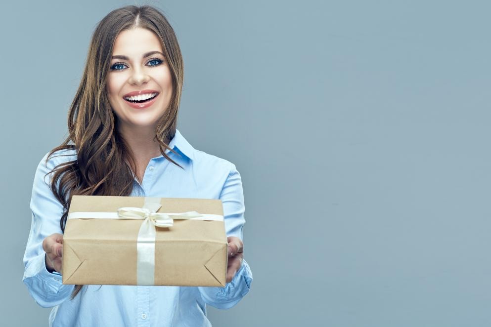 Das Foto zeigt eine Frau mit einem Geschenkpaket.