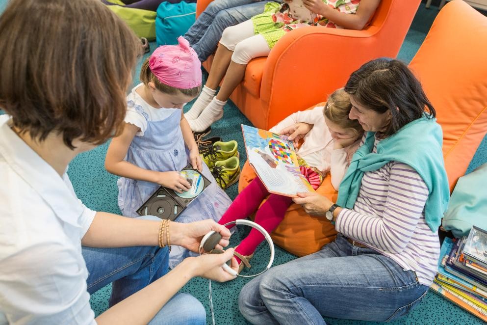 Gemeinsames Lesen, Foto: Andrea Fabry Das Foto zeigt Erwachsene und Kinder, die gemeinsam zusammensitzen und lesen. Foto: Andrea Fabry