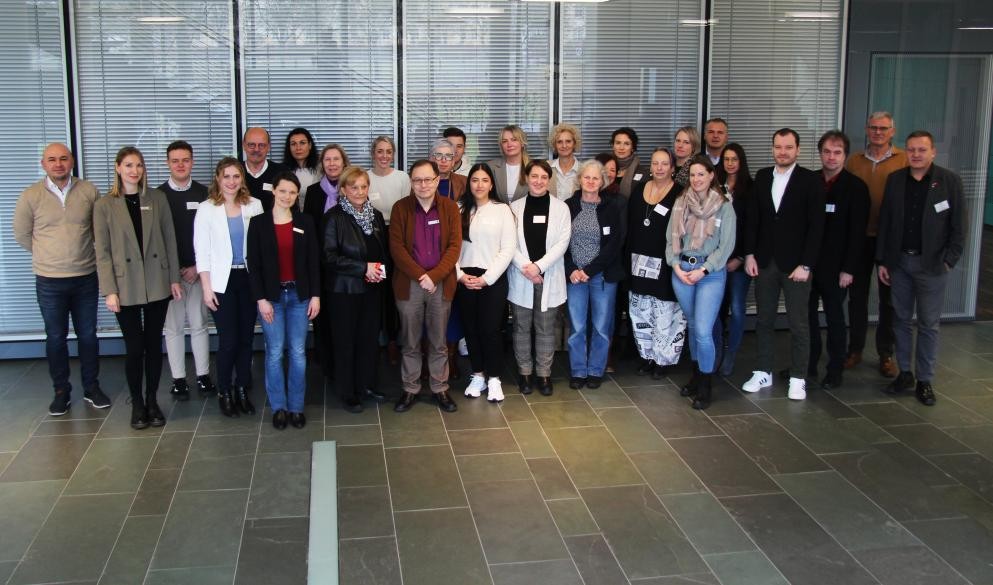 Im Landratsamt Rastatt kamen Vertreter von Kommunen und Organisationen zu einem Runden Tisch zusammen, um beim Thema „Internationale Fachkräfte“ stärker zu kooperieren. Foto: LRA/Janina Fortenbacher Eine Menschengruppe steht vor dem Kreistagssaal im Landratsamt Rastatt.